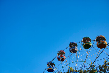 Colored Ferris wheel on a background of clear blue sky.