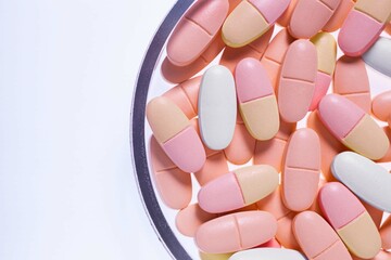 White orange pink pills in Petri dish gray background