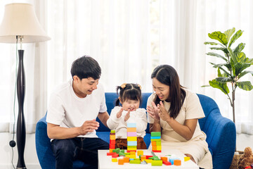 Obraz na płótnie Canvas Portrait of enjoy happy love asian family father and mother with little asian girl smiling activity learn and skill brain training play with toy build wooden blocks board education game at home