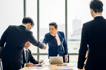 Image two asian business partners in elegant suit successful handshake together in front of group of casual business clapping hands in modern office.Partnership approval and thanks gesture concept