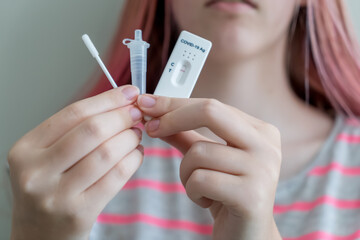 Teenage girl holding Covid-19 rapid antigen test cassette with negative result of rapid diagnostic test