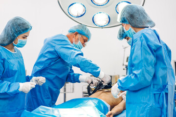 Professional anesthesiologist doctor medical team and assistant preparing patient to gynecological surgery performing operating with surgery equipment in modern hospital operation emergency room