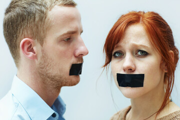 Theyve been silenced. A young couple looking sad with tape over their mouths.