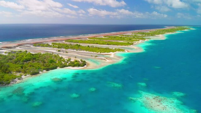 Aerial shot flying towards chain of small islands on tropical atoll in the South Pacific