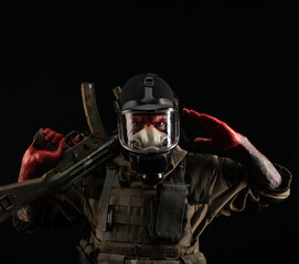 a man in a military uniform and a gas mask holds a weapon with bloody hands with an angry expression of emotions