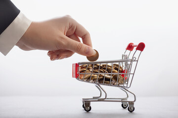 online commerce and banking concept, businessman's hand stacks coins in supermarket trolley,...