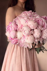 a young woman in a beautiful dress holds a large bouquet of freshly cut pink peonies, the concept of an online flower shop and delivery