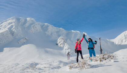 Ski touring couple high fiving on the top of mountain in the Low Tatras in Slovakia.