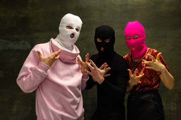 Group of young anonymous men andgirl wearing balaclava gesturing isolated on dark vintage background. Concept of safety, art, fashion, outrageous - obrazy, fototapety, plakaty