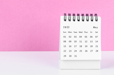 Obraz na płótnie Canvas May 2022 desk calendar on white table with pink background.