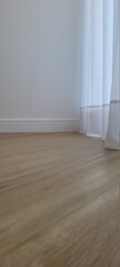 parede com cortina branca e piso de madeira
