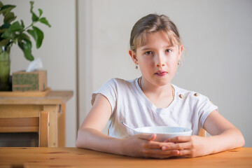 Naklejka premium Blonde teenage girl eating cereal for breakfast. Lifestyle portrait.