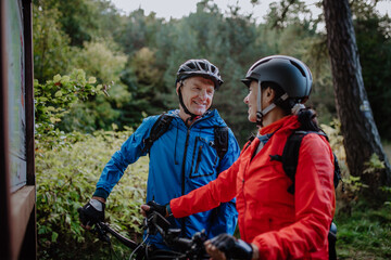 Happy senior couple bikers talking by map outdoors in nature in autumn day.