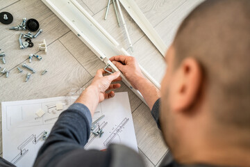 One man unknown caucasian male sitting on the floor at home Putting Together Self Assembly...