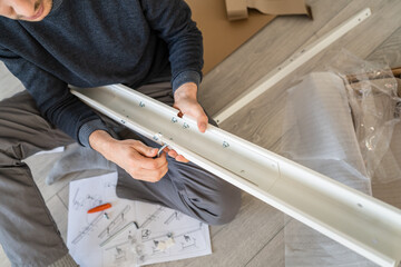 One man unknown caucasian male sitting on the floor at home Putting Together Self Assembly...