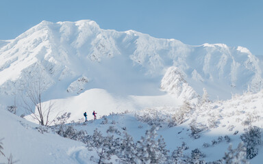 Fototapeta na wymiar Landscape view of ski touring couple hiking up a mountain in the Low Tatras in Slovakia.
