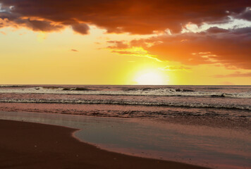 Waves at sea on sunset. Waves at sea during storm and wind. Wave from the sea goes on land to the beach. Splashing Waves in ocean on sunrise background, texture. Wave at Rising Storm at coastline.