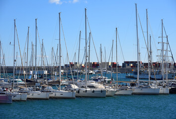 Fototapeta premium Yachts and motor boats in La Marina de Valencia, Spain. Luxury yacht and fishing motorboat in yacht club at Mediterranean Sea. Skiff and Sailboat in port. Yachting and sailing sport. Quai at ​Dock