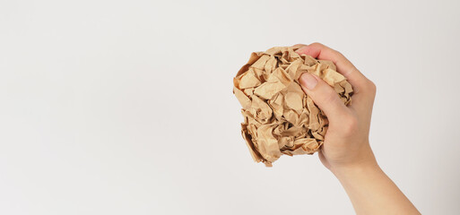 The man's hand is holding crumpled brown paper on white background.