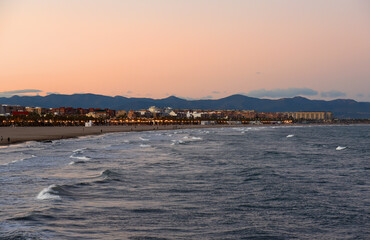 View on coastline and beach from La Marina de Valencia on the sea to the Las Arenas beach, Playa de las Arenas, Platja del Cabanyal and Playa de la Malvarrosa. Waves at sea on sunset.