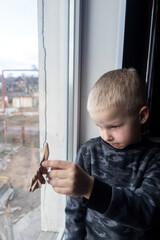 Russian attack on Ukraine. Child sits on the window and cries. Against the background of a...