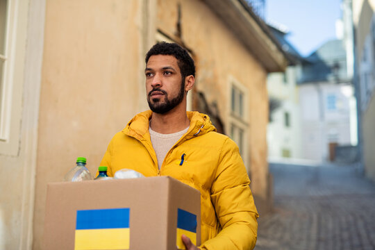 Volunteer cyrrying box with Humanitarian aid for Ukrainian refugees in street
