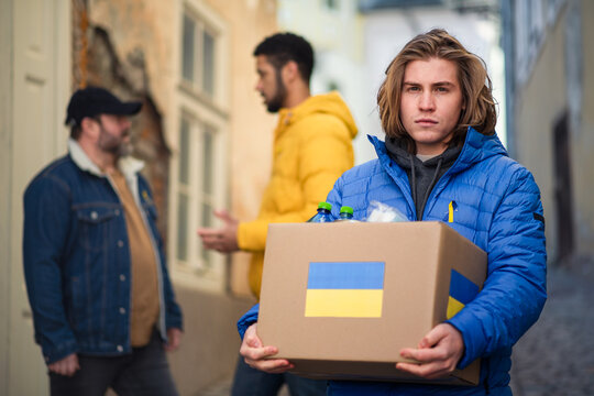 Team of volunteers collecting boxes with Humanitarian aid for Ukrainian immigrants in street