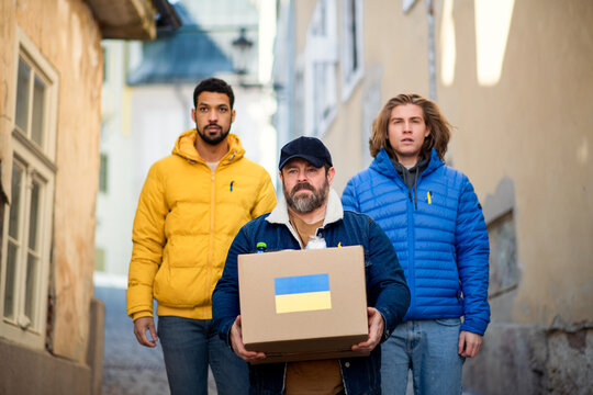 Team of volunteers collecting boxes with Humanitarian aid for Ukrainian immigrants in street