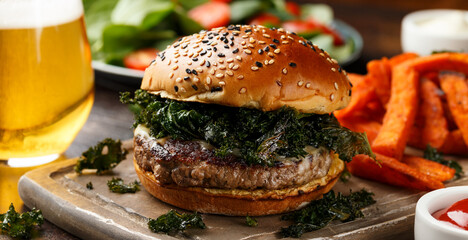 Juicy Beef burger with crispy kale, sweet potato fries and beer