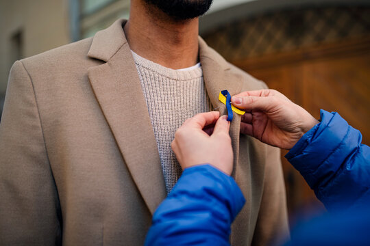 Protest organizer distributing Ukrainian blue and yellow ribbons to people protesting against war in Ukraine