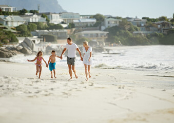 Enjoying the perfect family vacation. A happy young family walking down the beach together in the sunshine.