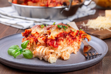 Mac and cheese with meatballs, mozzarella, tomato sauce and basil, on gray plate, horizontal