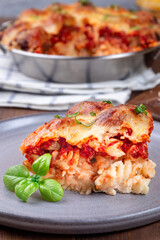 Mac and cheese with meatballs, mozzarella, tomato sauce and basil, on gray plate, vertical