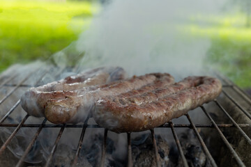 boerewors cooking over hot coals with smoke
