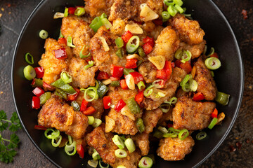 Stir fry salt and pepper pork loin with herbs in black bowl. Asian food