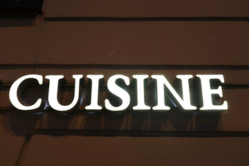 Cuisine signboard on wall of building at night