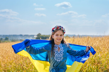 Girl wearing national dress and wreath of flowers holding flag of Ukraine