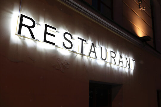 Restaurant signboard on wall of building at night