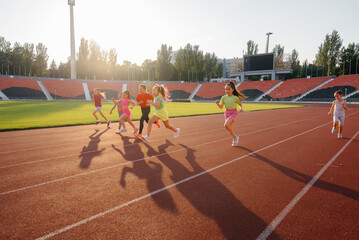 A large group of girls, got ready at the start before running at the stadium during sunset. A...