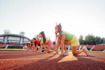 A large group of girls, got ready at the start before running at the stadium during sunset. A healthy lifestyle.
