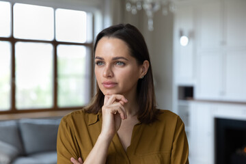 Head shot portrait pensive beautiful woman touch chin staring into distance looks thoughtful....