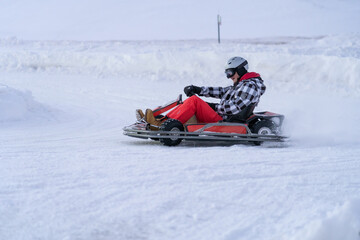 Go karting on icy track in winter. Adult karting driver on outdoor icy track - obrazy, fototapety, plakaty