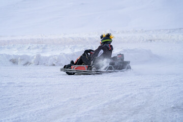Go karting on icy track in winter. Adult karting driver in action on outdoor icy track - obrazy, fototapety, plakaty
