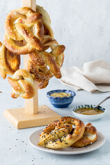 Homemade baked pretzels served with mustard dip and a tower of them in behind.