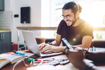 Laughing man typing on laptop meeting with coworkers