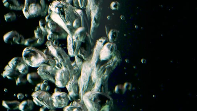 Black background. Shooting underwater. Stock footage. Impulsively moving bubbles of pure water and floating different particles.