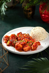 Asian food, rice with pork in sweet and sour sauce on a dark background