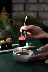 Female hands hold japanese chopsticks sushi in soy sauce, japanese cuisine