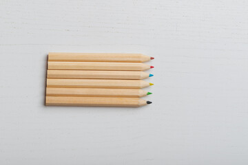 Wooden colored crayons on a white background.
