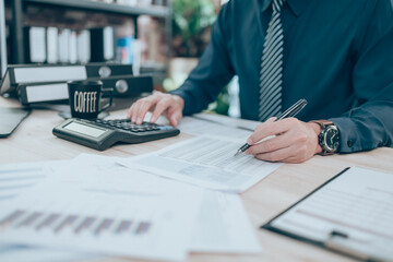 Accountant writing, checking and working on company data, document, report and calculator to calculate  on desk office. Accounting business concept.